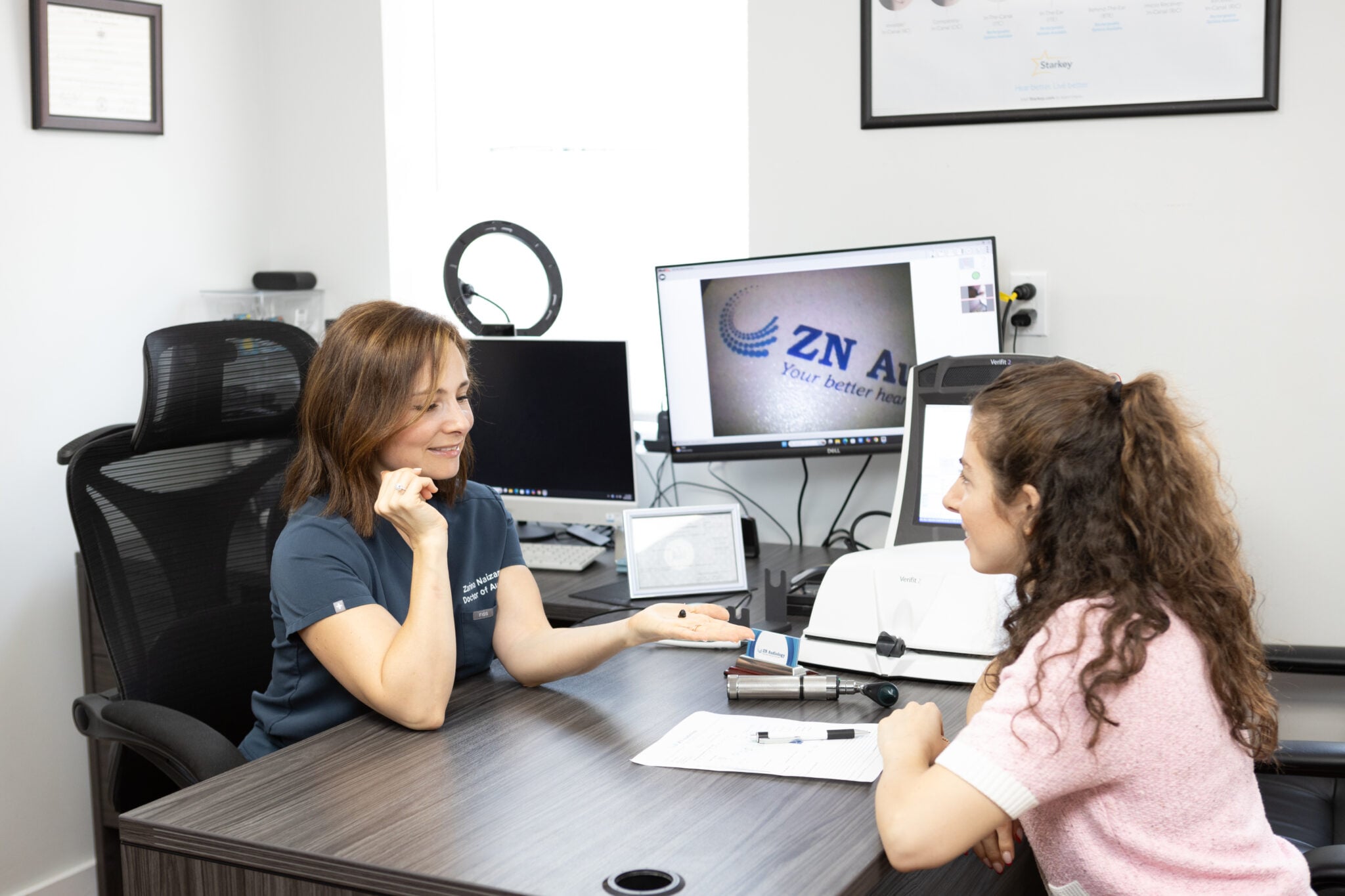 Dr. Zarina Naizam discussing hearing-aid technology with a patient at ZN Audiology